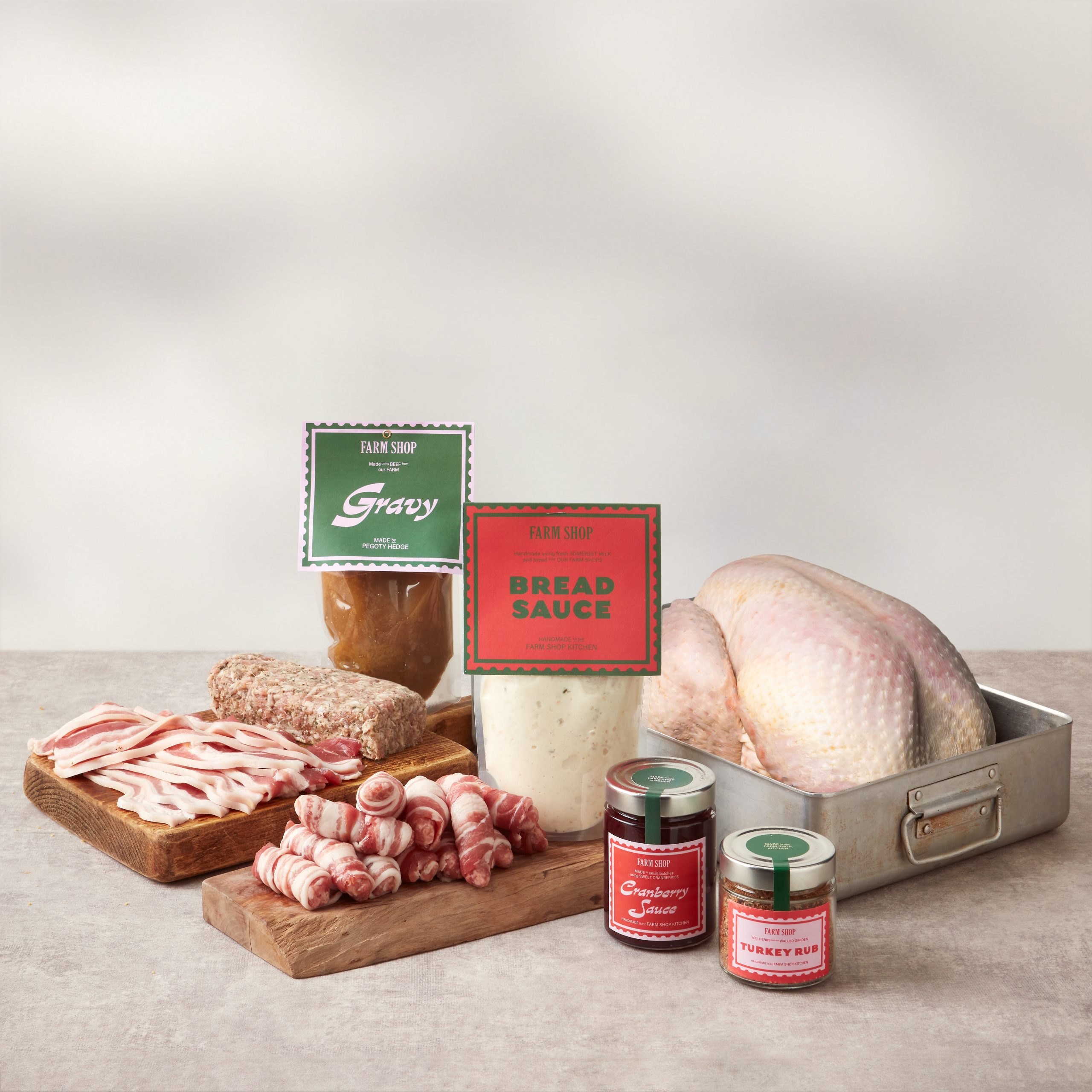 Whole turkey in a tray, with pigs in blankets, stuffing and bacon arranged on wooden boards, and various sauces