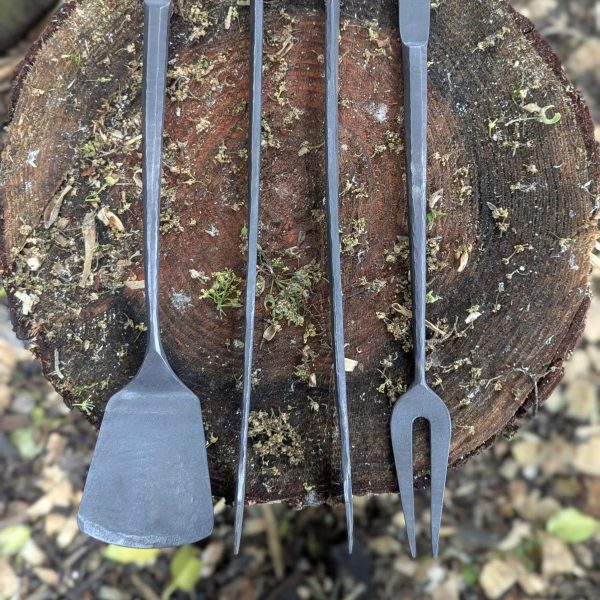 trio of stainless steel barbecue tools on a tree stump