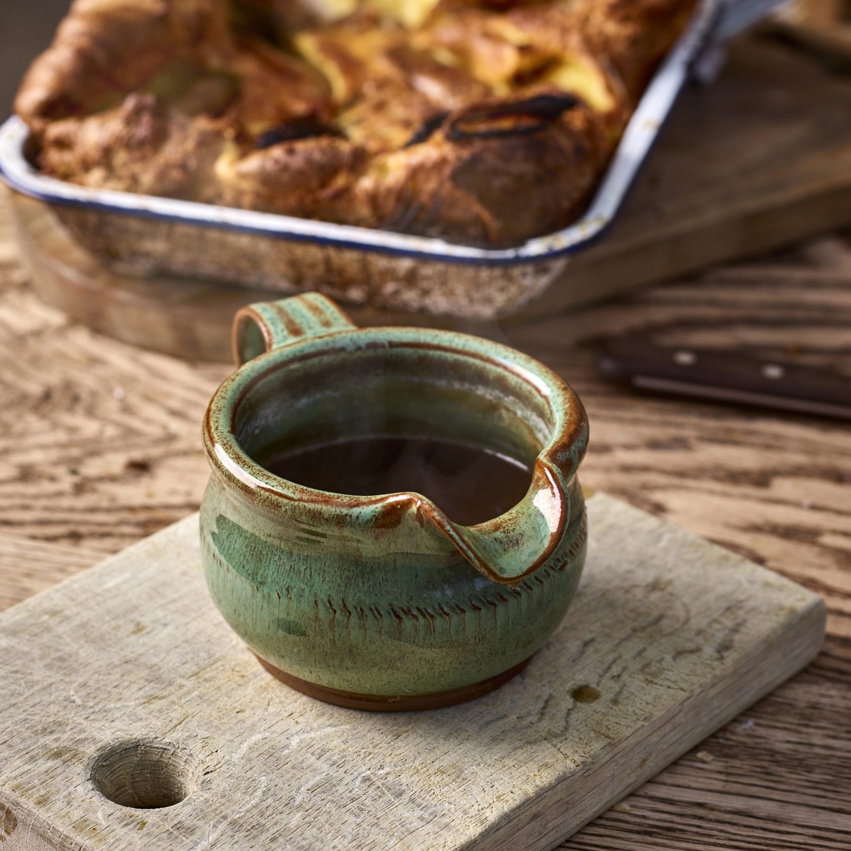 White horse pottery jug with gravy inside, and a baking tray in the background